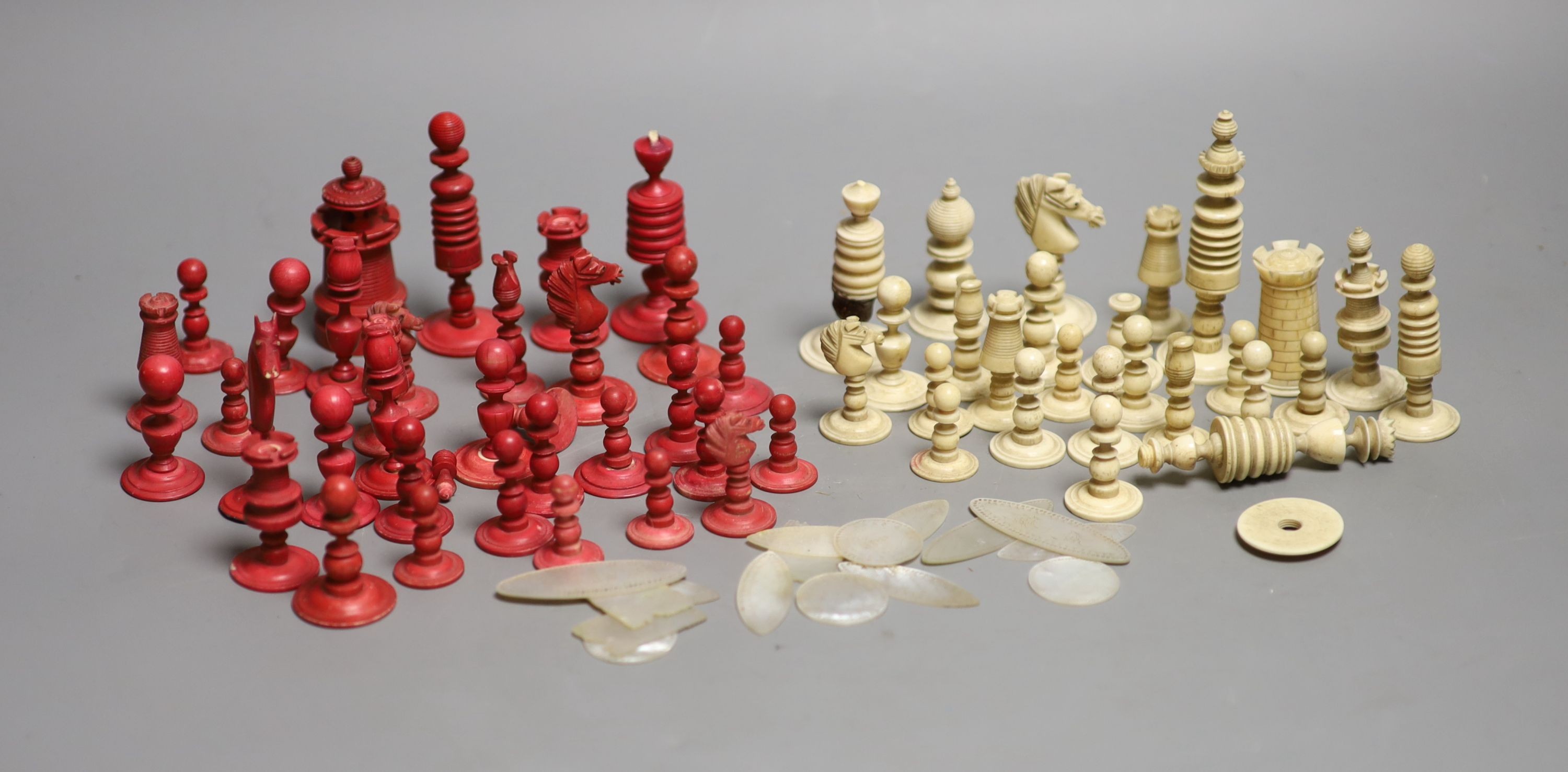 A set of 19th century red stained and natural bone chess pieces and a collection of etched mother of pearl bezique counters